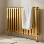 Stijlvolle gouden handdoekradiator in moderne badkamer met zachte verlichting en decoratieve handdoeken.
